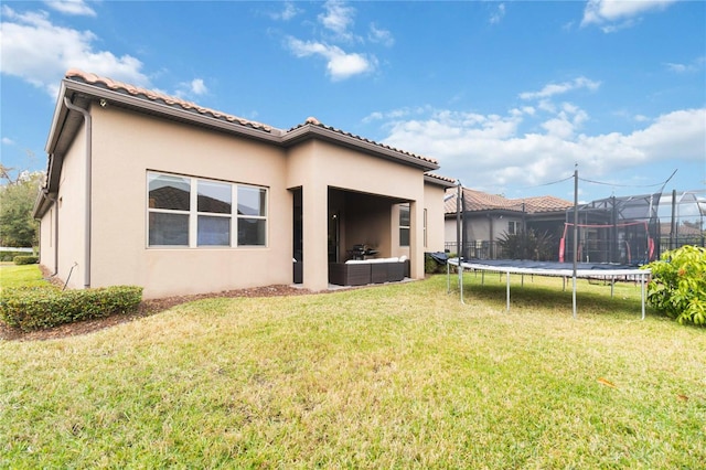 back of property featuring a lawn and a trampoline