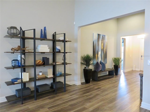 sitting room featuring a towering ceiling, baseboards, and wood finished floors