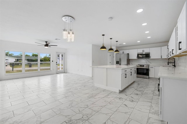 kitchen featuring appliances with stainless steel finishes, tasteful backsplash, decorative light fixtures, white cabinets, and a kitchen island