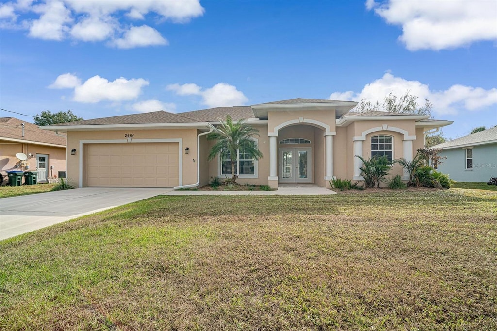 view of front facade with a garage, a front yard, and french doors