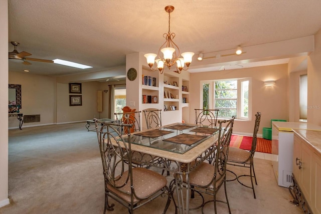 carpeted dining space with a textured ceiling, built in shelves, and ceiling fan with notable chandelier