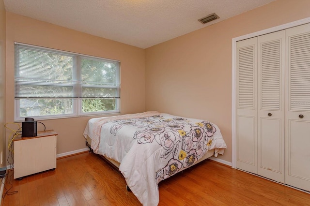 bedroom with wood-type flooring, a textured ceiling, and a closet