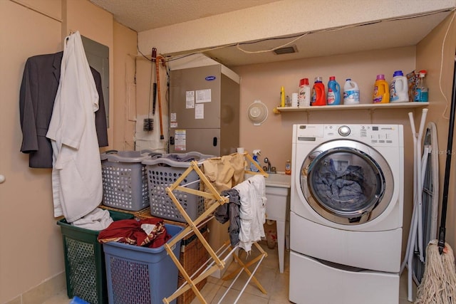 washroom with washer / clothes dryer, light tile patterned floors, and a textured ceiling