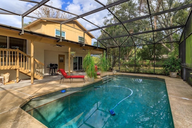 view of swimming pool featuring glass enclosure, ceiling fan, area for grilling, and a patio