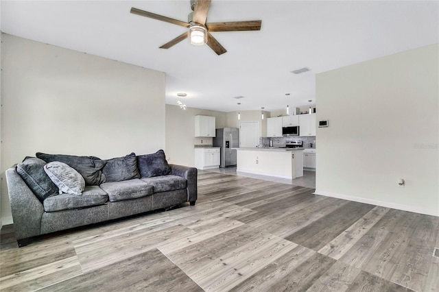 living room featuring ceiling fan and light hardwood / wood-style flooring