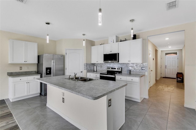 kitchen with a kitchen island with sink, white cabinets, sink, appliances with stainless steel finishes, and decorative light fixtures