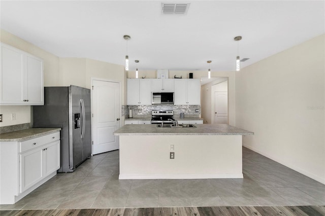 kitchen with a center island with sink, stainless steel appliances, and decorative light fixtures