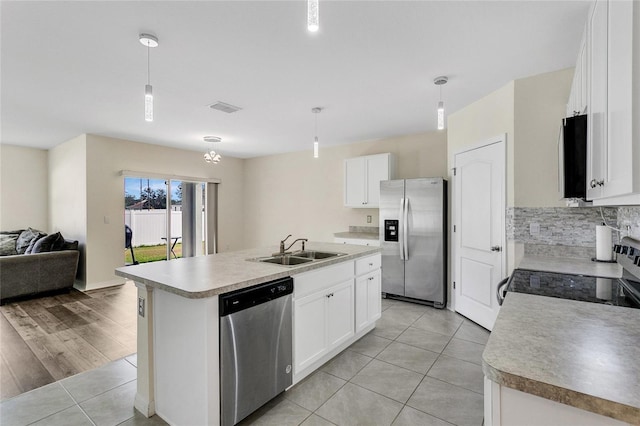 kitchen featuring a center island with sink, white cabinets, hanging light fixtures, and appliances with stainless steel finishes