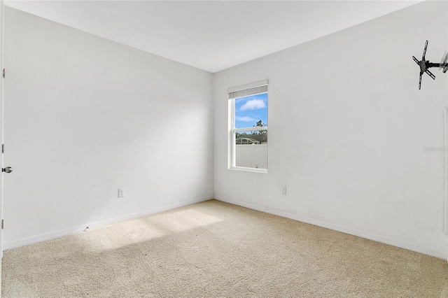 unfurnished room with baseboards and light carpet