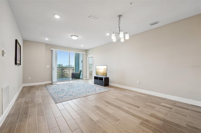 unfurnished living room featuring light wood-type flooring and a chandelier