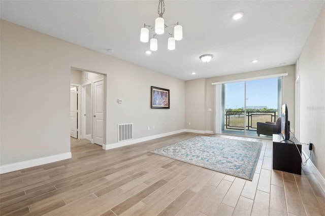 unfurnished living room with light hardwood / wood-style floors and a notable chandelier