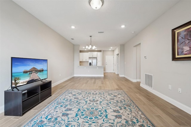 living room with light hardwood / wood-style flooring and an inviting chandelier