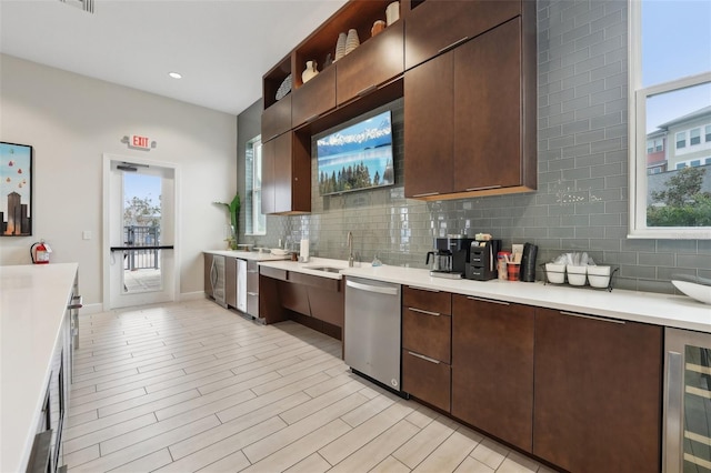 kitchen with stainless steel dishwasher, tasteful backsplash, dark brown cabinets, washer / dryer, and beverage cooler