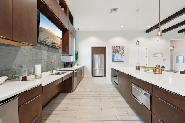 kitchen featuring dark brown cabinetry, stainless steel appliances, sink, beam ceiling, and decorative light fixtures