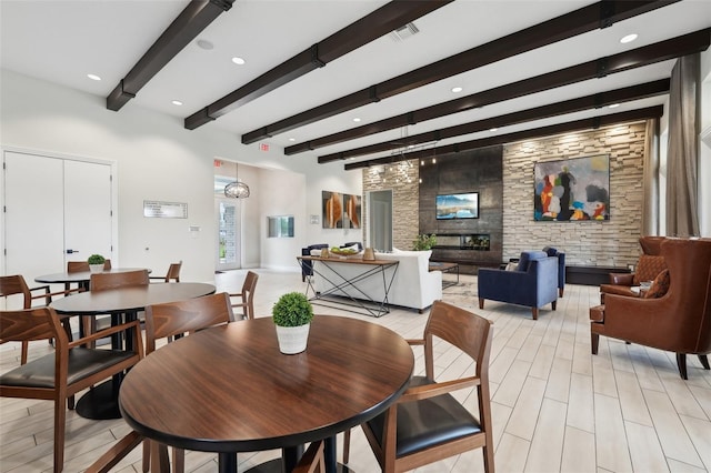 dining space featuring a stone fireplace and beamed ceiling