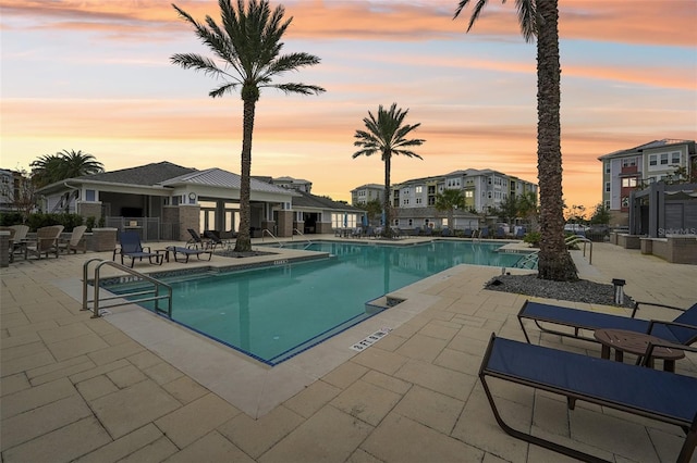 pool at dusk featuring a patio