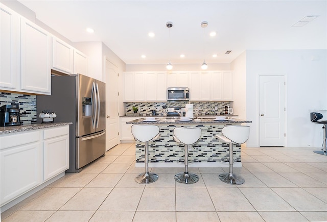 kitchen with white cabinets, light stone counters, light tile patterned floors, and appliances with stainless steel finishes