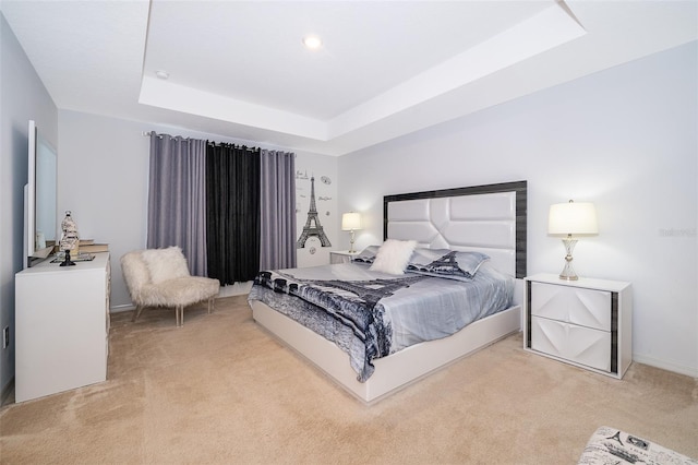 bedroom featuring a tray ceiling and light carpet