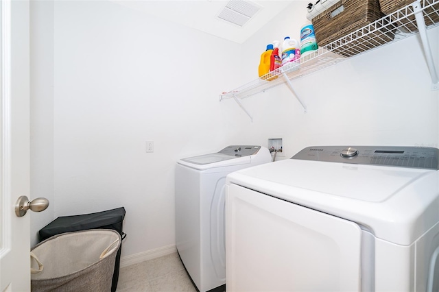 clothes washing area featuring washer and dryer and light tile patterned flooring