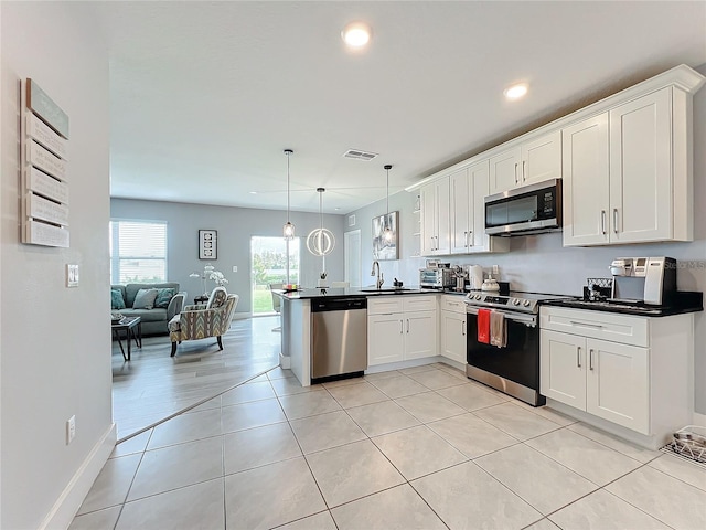 kitchen with kitchen peninsula, stainless steel appliances, sink, decorative light fixtures, and white cabinets