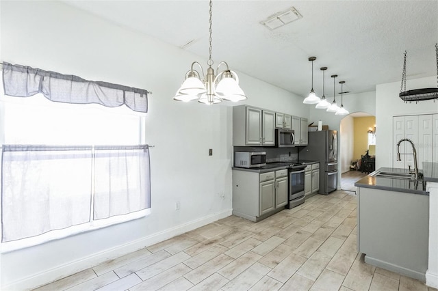 kitchen with stainless steel appliances, a notable chandelier, gray cabinetry, and sink