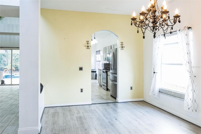 interior space with ceiling fan with notable chandelier, light wood-type flooring, and a healthy amount of sunlight