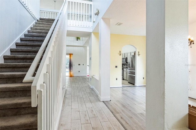 staircase featuring a high ceiling and hardwood / wood-style flooring