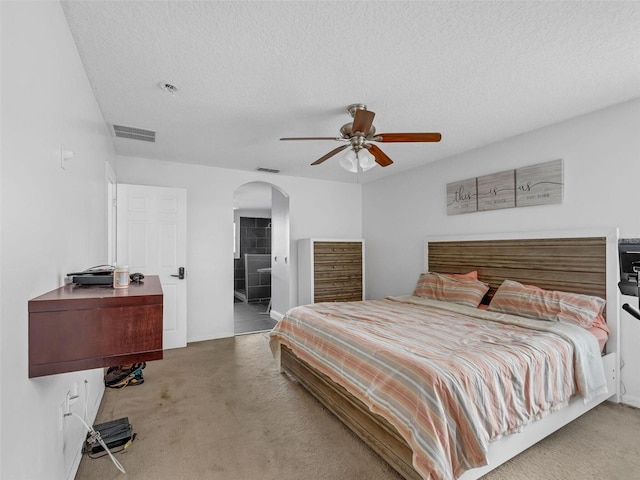 bedroom featuring a textured ceiling, ceiling fan, carpet floors, and ensuite bathroom