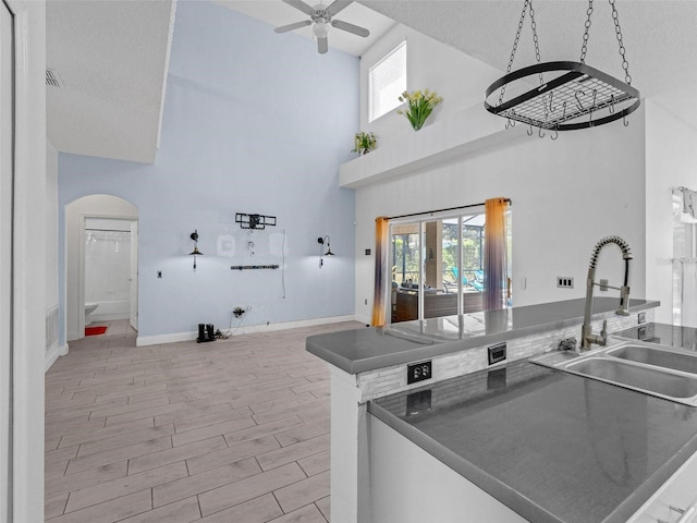 kitchen with a textured ceiling, ceiling fan, sink, and a high ceiling