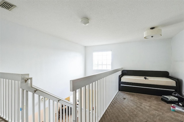 corridor with a textured ceiling and carpet floors