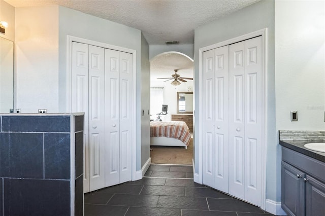 bathroom with vanity, ceiling fan, and a textured ceiling