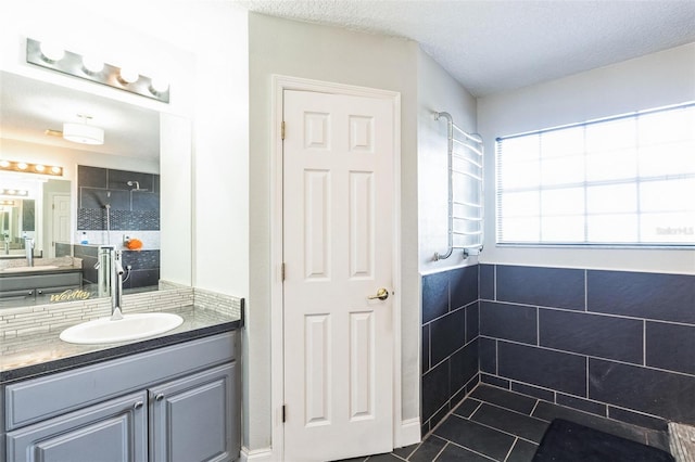 bathroom with tile patterned flooring, a textured ceiling, vanity, and walk in shower