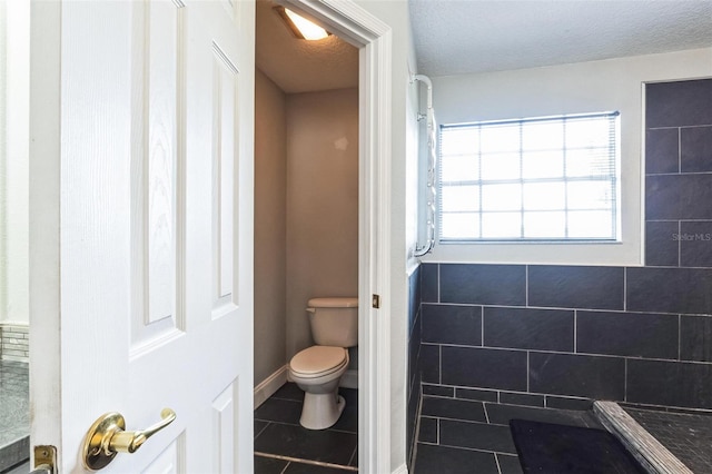 bathroom with tile patterned flooring, a textured ceiling, and toilet