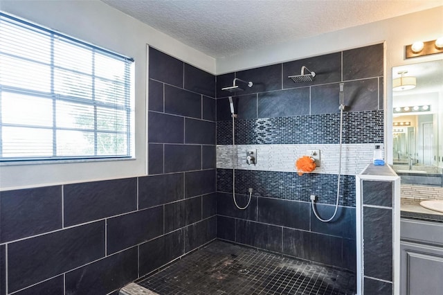 bathroom featuring a tile shower, a wealth of natural light, vanity, and a textured ceiling