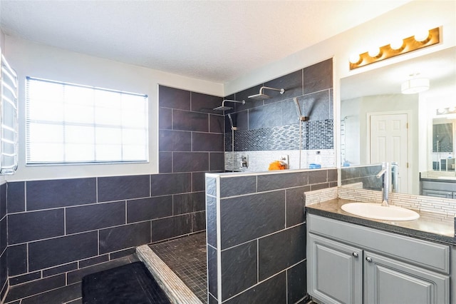 bathroom featuring tiled shower, vanity, and tile walls