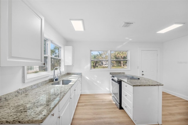 kitchen with sink, light stone counters, white cabinetry, and electric stove