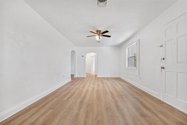 unfurnished room featuring arched walkways, visible vents, a ceiling fan, light wood-type flooring, and baseboards