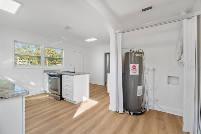 interior space featuring light stone counters, electric water heater, visible vents, white cabinetry, and electric stove