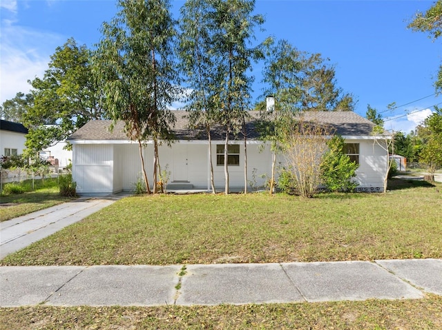 ranch-style home featuring a shingled roof and a front lawn