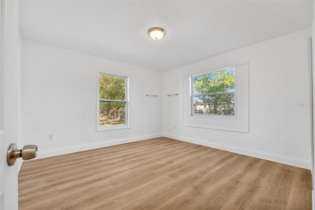 unfurnished room featuring a healthy amount of sunlight, light wood finished floors, and baseboards