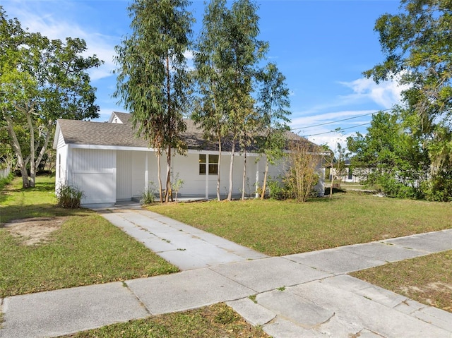ranch-style home with driveway, a front lawn, and roof with shingles