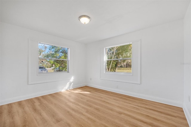unfurnished room with baseboards, light wood-style flooring, and a healthy amount of sunlight
