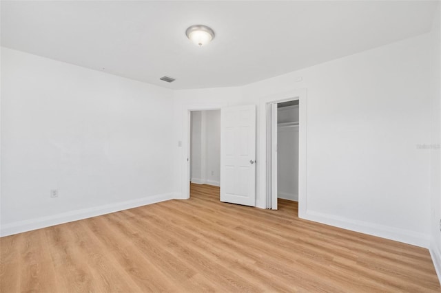 unfurnished bedroom with baseboards, visible vents, a closet, and light wood-style floors