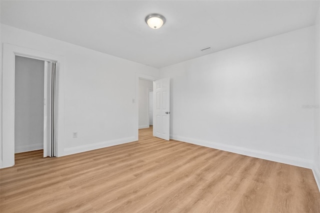 spare room featuring baseboards, visible vents, and light wood-style floors