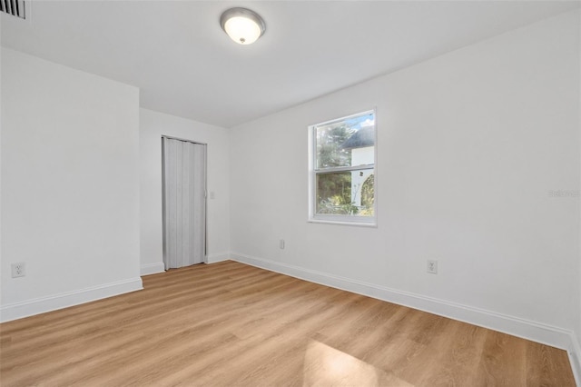 unfurnished room featuring light wood-style flooring, baseboards, and visible vents