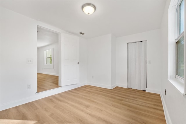unfurnished room featuring baseboards, light wood-type flooring, and visible vents