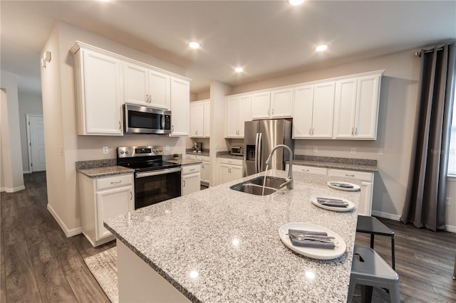 kitchen with a kitchen island with sink, sink, white cabinets, and appliances with stainless steel finishes