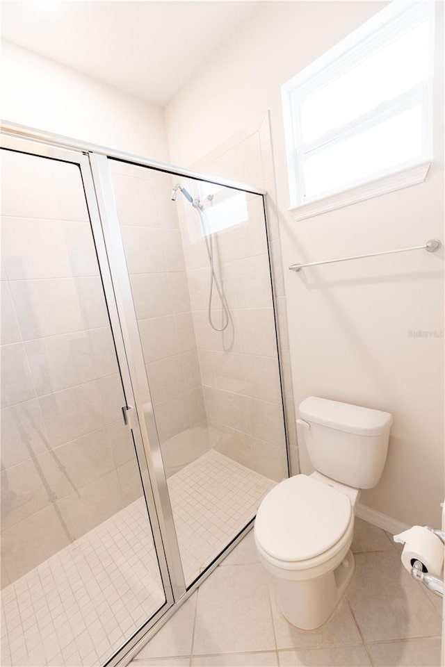 bathroom featuring tile patterned floors, toilet, and a shower with door