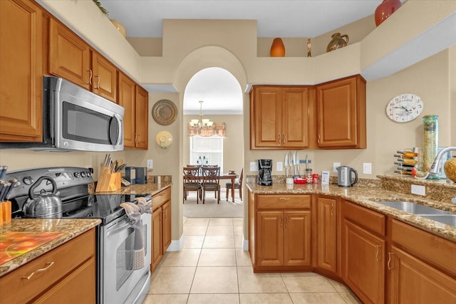 kitchen featuring sink, stainless steel appliances, an inviting chandelier, light stone counters, and light tile patterned floors