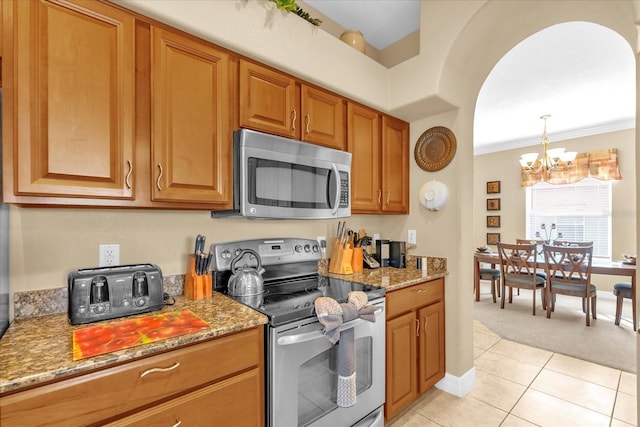 kitchen with stainless steel appliances, light stone counters, a notable chandelier, pendant lighting, and light tile patterned floors